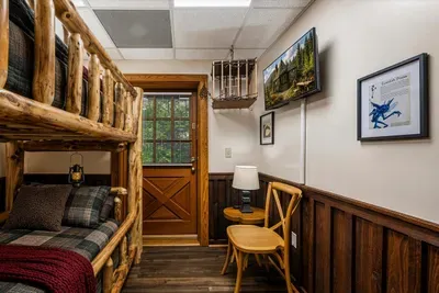 A bunk room with a log-post bed, mountain artwork, and its own quiet corner desk. Room for the kids — or for the one friend who still insists that he doesn't snore.