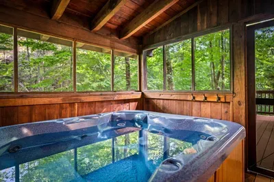 A year-round hot tub on a screened porch wrapped in windows — steam rising, forest glowing green, not a neighbor in sight. Can you picture your first night here?