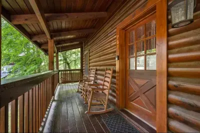 Rocking chairs line the covered balcony where morning fog drifts through the trees. Coffee, a quilt, and an hour with nowhere to be — guests' favorite way to start a day here.