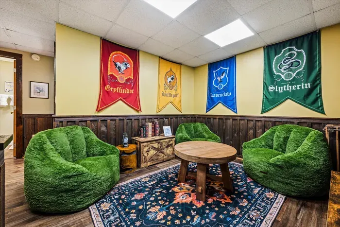 Wizarding-themed game lounge downstairs — house banners, oversized moss-green bean bags, and a table built for late-night card games. Kids claim it first; adults never leave.