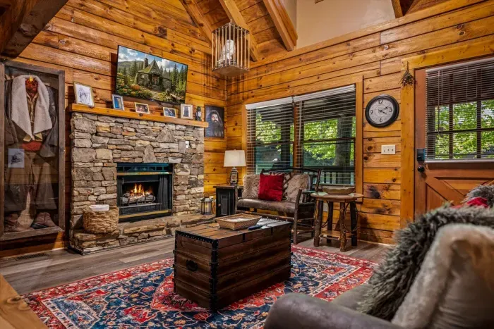 Board games on the trunk coffee table, firelight throwing gold across the log walls, forest framed in every window. This is the room the whole cabin gravitates toward.
