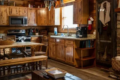 Coffee bar, full-size range, deep sink, and a window looking straight into the woods — mornings start right here, mug in hand, long before the rest of the cabin stirs.