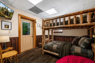 Handcrafted log bunk beds, plaid bedding, and a bean bag for whoever loses the top-bunk debate. This is kid headquarters, and they'll disappear into it for hours.