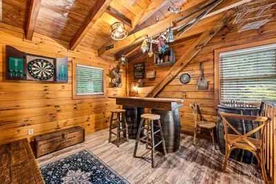 The upstairs game loft comes with a barrel-height pub table and a dartboard on the wall — tournament brackets, trash talk, and a vaulted ceiling over all of it.
