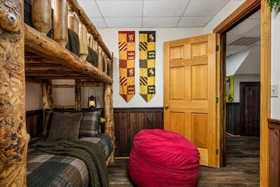 A themed bunk room with house banners over a handcrafted log bunk — sorted, settled, and asleep by nine. This is the photo the kids will point to when you show them.
