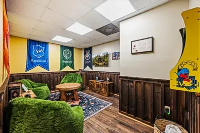 The lower-level game room goes all in on the wizarding world — house banners, an arcade cabinet, and squishy green armchairs. It's the reason kids beg to come back.