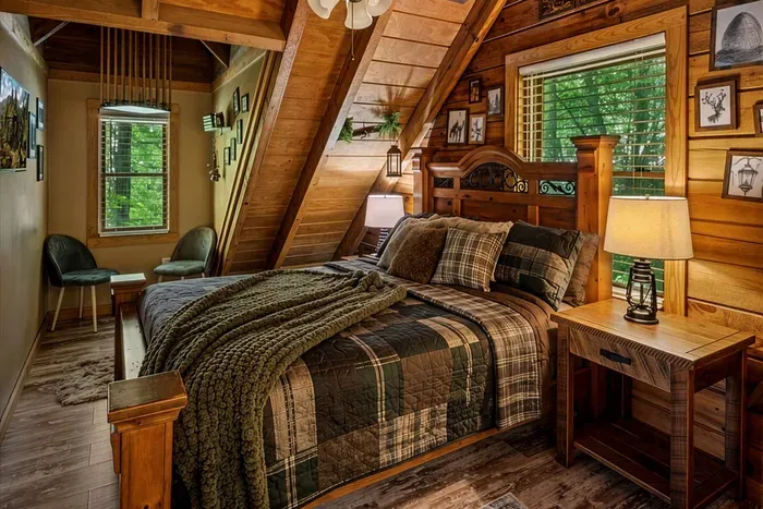 A private loft retreat with a plaid-quilted bed, lantern lamp, and a chair angled toward the window. Read until the woods go dark and the crickets take over the soundtrack.