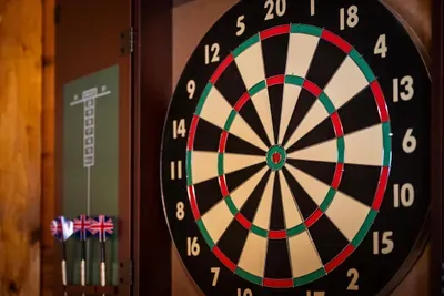 A tournament-ready dartboard in the game loft — the after-dinner ritual, with mountain quiet outside the window and the scoreboard steadily filling up inside.