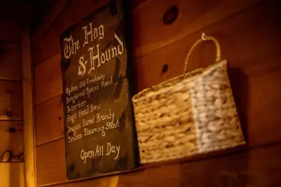 A hand-painted tavern menu board on the log wall — the cabin's own pub, open all day. This place is themed from the doorknobs up, not just decorated on one shelf.