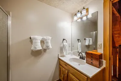 A wide vanity, big mirror, and rolled towels stacked and ready to go. Multiple full baths mean nobody's waiting in the hallway on an early hiking morning.