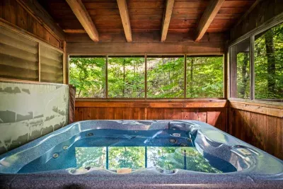 Slip into the bubbling hot tub while the forest presses against wraparound windows — screened, private, and yours alone. Steam, birdsong, and treetops after a long mountain day.