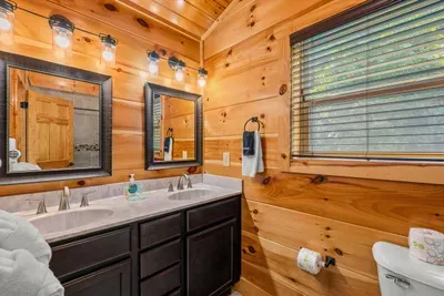 Two sinks, framed mirrors, and a bright window