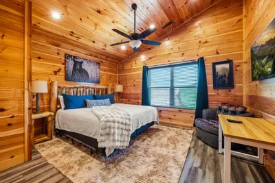Bedroom with a desk, a fan, and a window to the woods