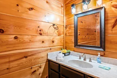 Full bath with a framed mirror and knotty pine walls