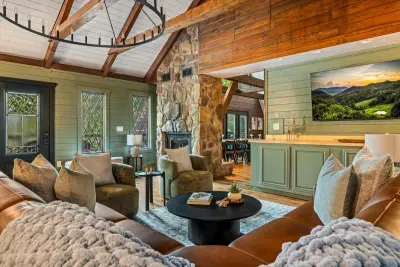 Curl up on leather sofas beneath hand-hewn beams — chunky knit throws within reach, a stone fireplace anchoring the room. Mountain-cabin comfort, dialed all the way up.