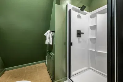 Tucked-away bath in deep forest green with a private walk-in shower — quick, clean, and convenient for a full house. One more spot to rinse off after the trails.