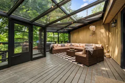 Glass-ceiling sunroom wrapped in treetops — sink into the sectional with a book while filtered light and forest quiet do the rest. Guests' favorite spot to lose an afternoon.