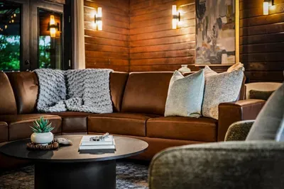 Deep leather sectional under warm wood walls and soft sconce light — room for everyone to pile in for movie night. The couch you won't want to leave.