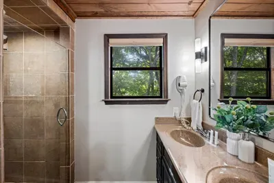 Tiled walk-in shower plus a double vanity and forest-facing window — rinse off the trail and start over fresh. A full bath built for a busy, happy houseful.