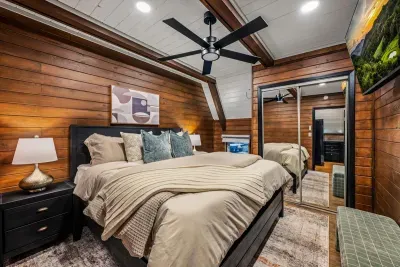 Warm wood-paneled bedroom with soft lighting and a bed built for sinking in. Private, quiet, and yours — the kind of room that makes sleeping in the plan.