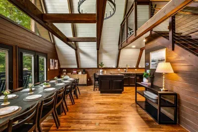 Gather-round dining under a soaring A-frame ceiling with the loft rising overhead — set the table, pour the wine, let the evening stretch. Room for everyone to pull up a chair.