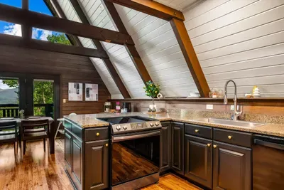Fully stocked chef's kitchen with granite counters, stainless appliances, and A-frame windows pouring the treeline right in. Cook big, gather close, keep the views on the menu.