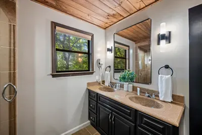 Double-vanity bath with granite counters and a window framing the treeline — space for two to get ready without the morning traffic jam. Small luxury, big difference on a group trip.