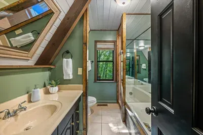 Forest-green ensuite with a bright window, framed mirror, and room to move — a calm, well-kept space to reset morning and night. The details here make the difference.