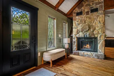 Step inside to a floor-to-ceiling stone fireplace and warm wood underfoot — the welcome that tells you you've arrived somewhere special. Drop the bags and settle in.