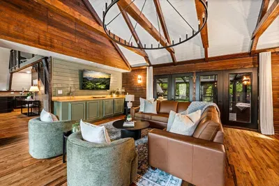 Great room flows right into the wet bar — pour a drink, claim a couch, and settle in under the wrought-iron chandelier. Open-concept living built for easy nights in with the crew.