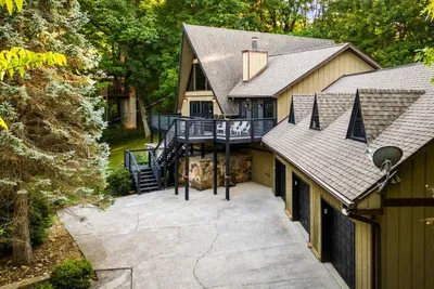 Sweeping look at the property — A-frame peak, wraparound decks, and green in every direction. Space for a big group and privacy for all of them.