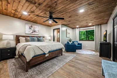 Wake to dappled forest light in the king suite — vaulted wood ceiling, cozy sitting nook, and a window full of green. The kind of sleep you only get up here.