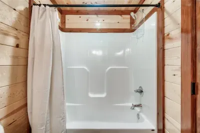 Crisp white tub and shower tucked into warm cabin walls — sparkling clean and perfectly functional. Because a great trip starts and ends with a great shower.
