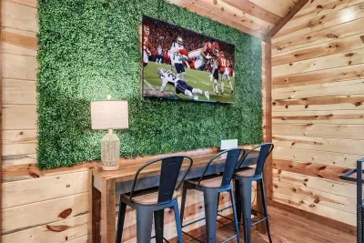 Living green hedge wall, a massive flat-screen, and bar-stool seating — game day, movie night, or both. Your cabin's media setup was built for the moment.