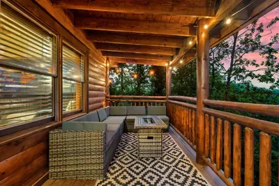 Wicker sectional, fire table, and a rose-gold Smoky Mountain sunset framed by the timber pavilion — the last hour of daylight hits differently from this spot.