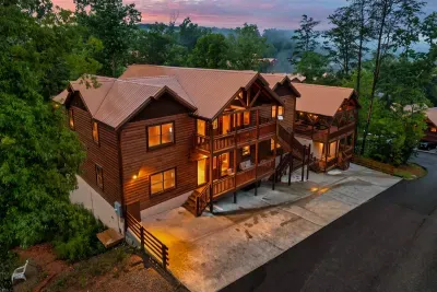 Bird's-eye view of the full property — two cabins, multiple deck levels, generous parking, and a mountain forest surrounding it all. Your group's private mountain retreat, laid out in full.