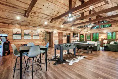 Vaulted game room with foosball, bar-height seating, and hardwood floors that beg for a tournament — this is where your group's rivalry officially begins.