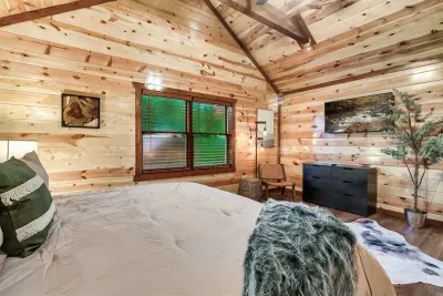 Crisp white linens, a teal throw, and a window full of Smoky Mountain green — wake up here and your first thought will be to never check out.