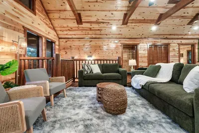 Cabin living at its most comfortable — plush sectionals, woven accents, and warm wood walls that make you forget there's a world outside. Good luck leaving.