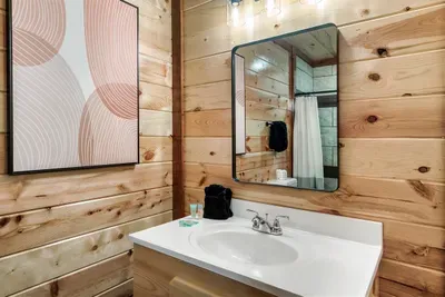 Warm knotty pine walls meet clean white fixtures — a cabin bathroom that feels polished, not rustic. Fresh, bright, and ready for your morning routine.