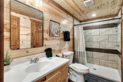 Full private bathroom with soaking tub, vanity, and tile surround — everything your group needs, nothing shared with strangers. Clean, complete, and cabin-charming.