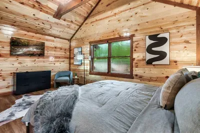 Crisp king bed, blue accent chair, and sunlit cabin windows — a private escape within the escape, where mountain air and deep sleep come standard.