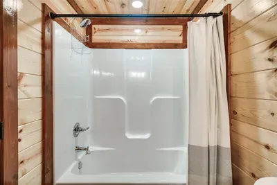 Gleaming white tub and shower — hotel-clean in a cabin setting. Hot water, fresh towels, and nothing to worry about after a long day on the trails.