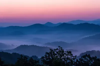 Layered Smoky Mountain ridges dissolve into a rose-gold dusk — this is the view that makes guests extend their stay. Can you blame them?