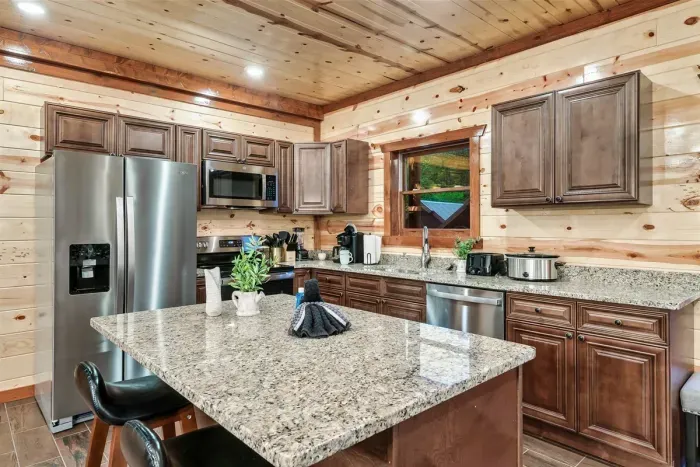 Granite countertops, stainless fridge with ice maker, and a kitchen island made for prep work — this kitchen is ready for the big group breakfast before the big group adventure.