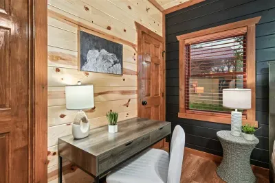 King bedroom with a built-in workspace, warm lamp light, and navy accent wall — for when the mountains are calling but the inbox won't wait. Work optional. Rest guaranteed.