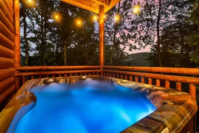 Private hot tub glowing electric blue against a Smoky Mountain twilight sky ablaze in crimson and violet — this is the image you'll see when someone asks how the trip was.