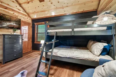 Sleeping 4 in style — this wood-paneled bunk room with timber ladder and mountain-lodge finishes gives the kids their own retreat inside the retreat.