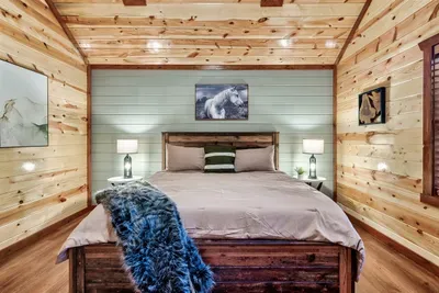Drift off under a soaring pine ceiling with warm cabin light and a king bed dressed for deep mountain sleep — this room earns its place as a guest favorite.