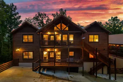 Warm cabin lights against a blazing crimson sky — the Smokies put on a show every evening, and your deck has the best seat in the house. No reservation required.